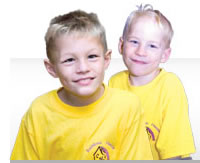 Two lads smiling into the camera, they are both wearing yellow 'Rainbow House' t-shirts